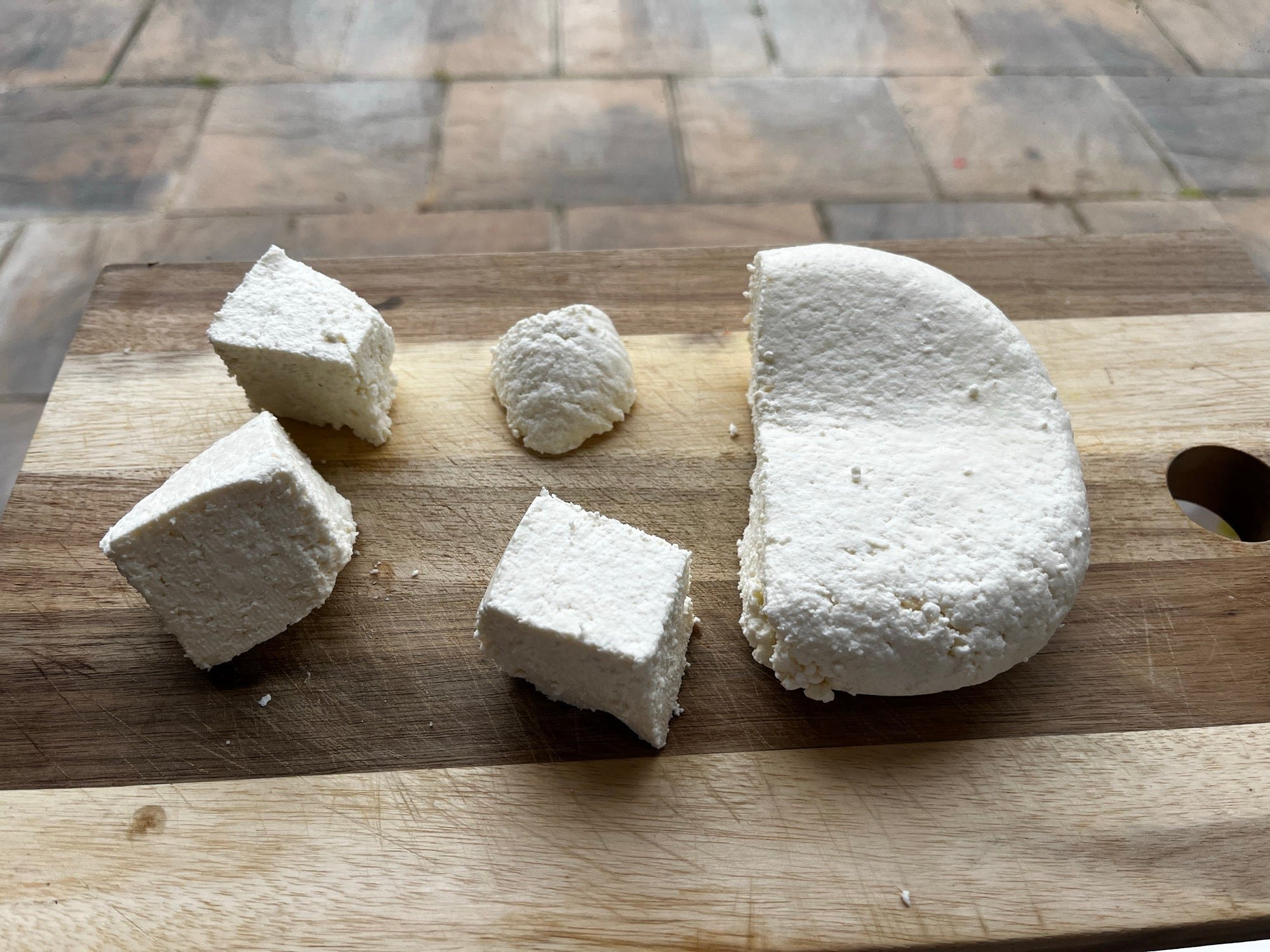 A block of Daio paneer cut into pieces on a chopping board
